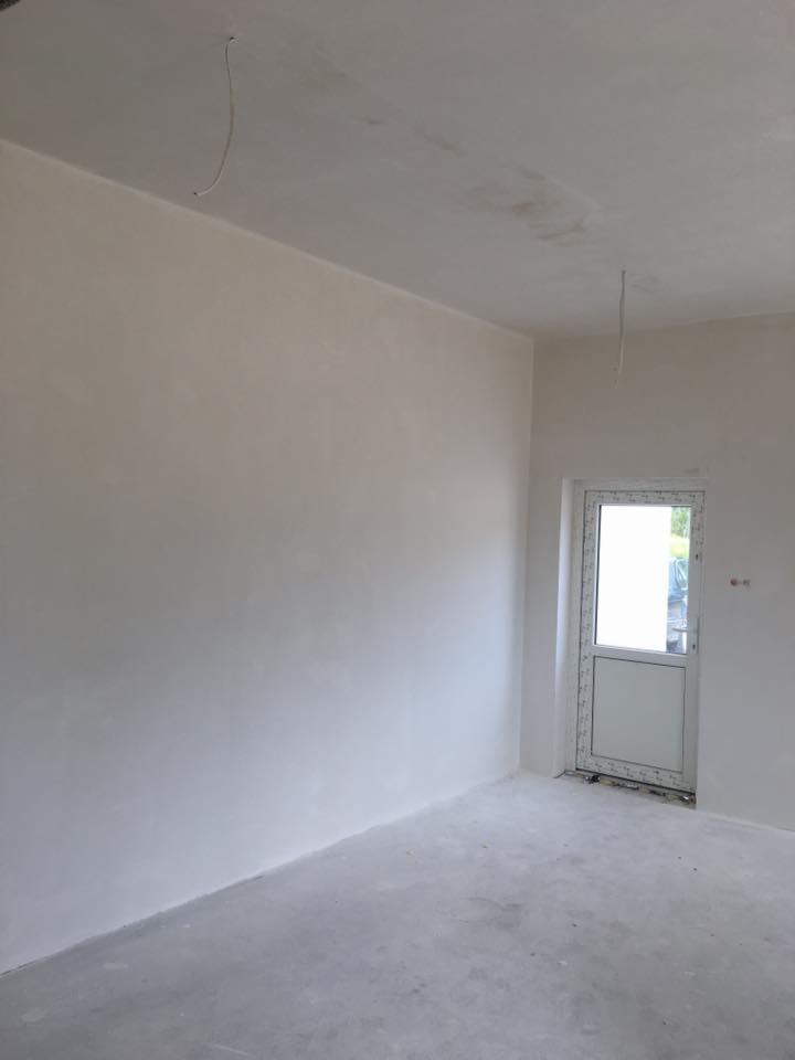 Surowe wnętrze pokoju w Lidzbarku po nałożeniu gładzi, widoczne niedoskonałości na ścianach i suficie, przygotowane do dalszych prac wykończeniowych.