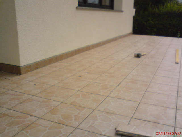 Ułożona podłoga z płytek ceramicznych na zewnątrz budynku w Tarnowskich Górach, widoczny gumowy młotek i poziomica.