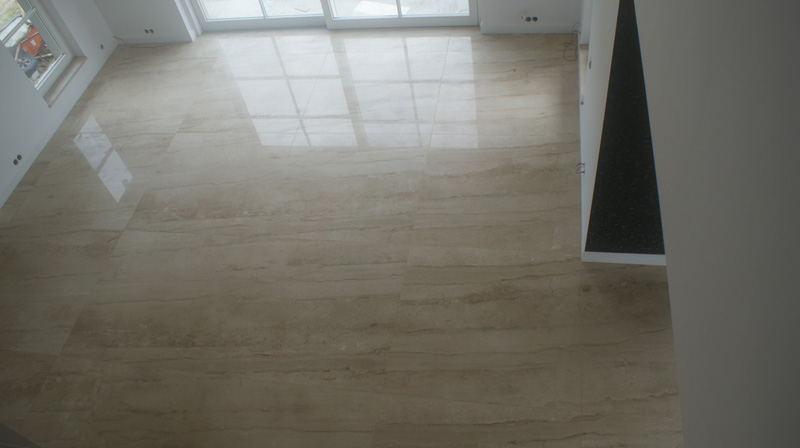 Ułożona marmurowa posadzka wewnętrzna z widocznymi refleksami światła z okien, ukazująca naturalny wzór kamienia.