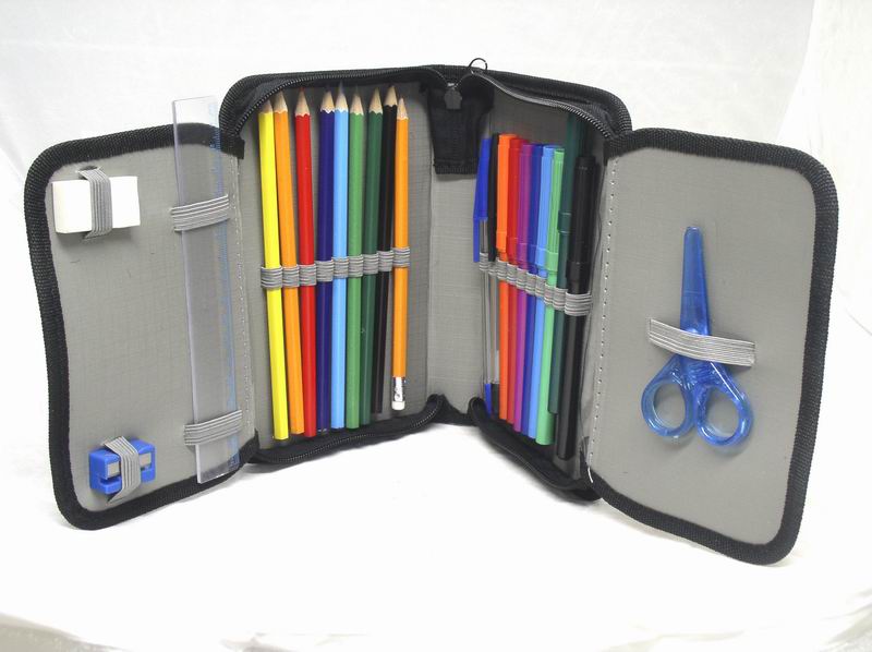 Otwarty piórnik z wyposażeniem: kolorowe kredki, pisaki, linijka, gumka i niebieskie nożyczki, wszystko uporządkowane w elastycznych uchwytach.