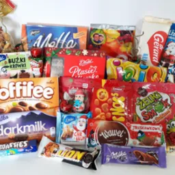 Bogaty zestaw słodyczy różnych marek, w tym czekolady Milka Darkmilk, Toffifee, Ptasie Mleczko i żelki, tworzący kompozycję prezentową na białym tle.