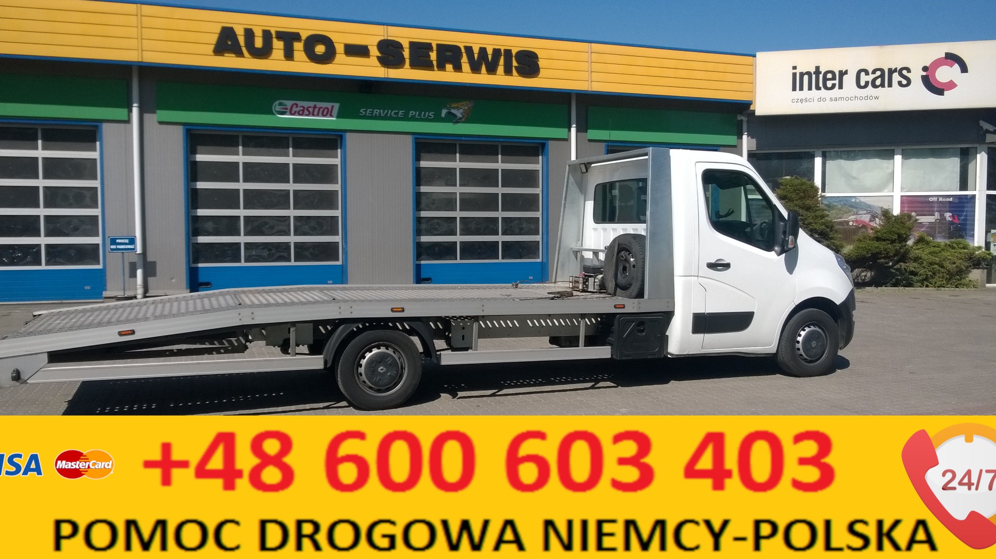 Biała laweta na tle budynku auto-serwisu z reklamą Castrol i Inter Cars, widoczny numer telefonu i napis Pomoc Drogowa Niemcy-Polska.