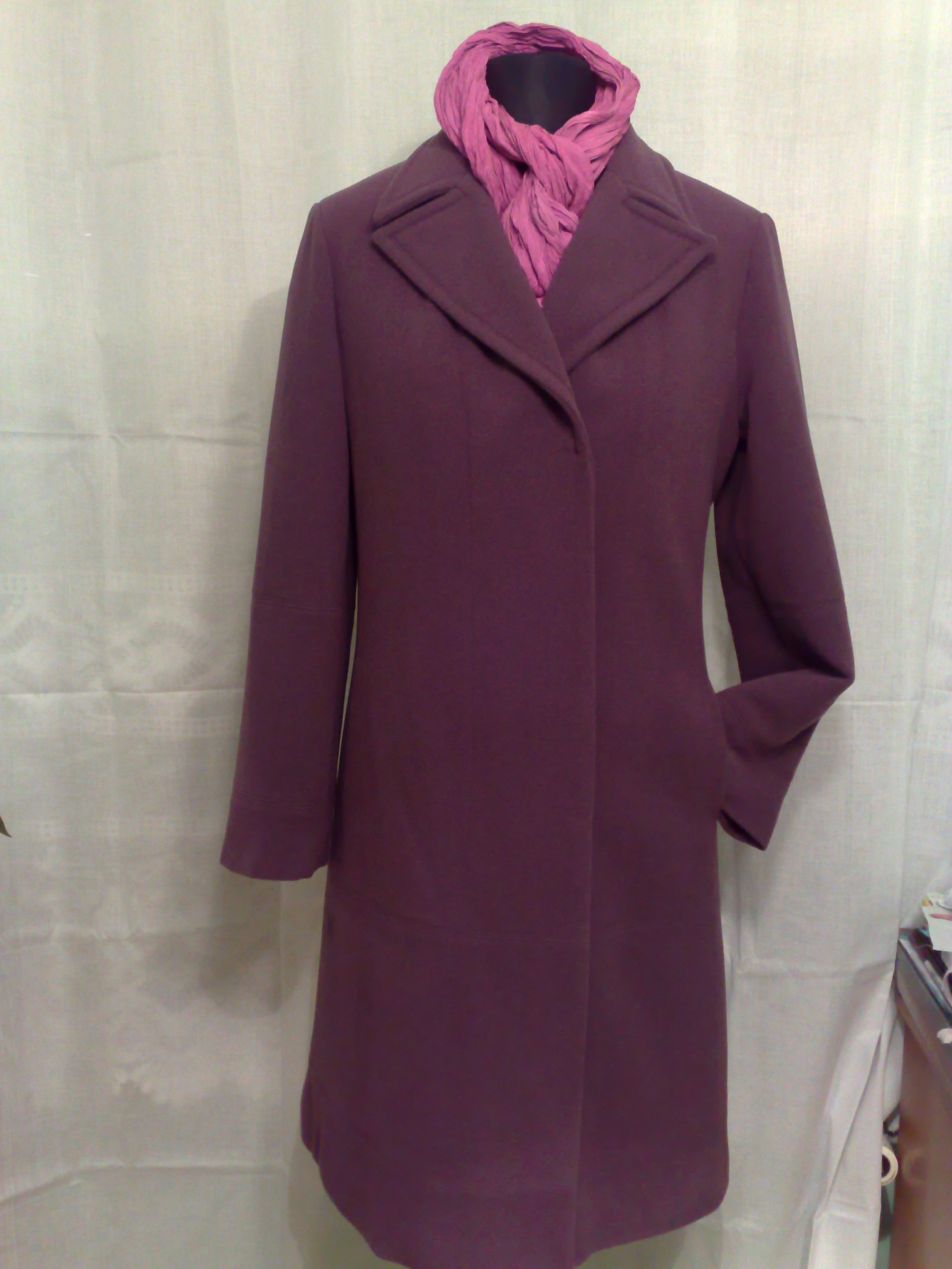 Damski płaszcz wełniany w kolorze burgundowym na manekinie z różowym szalem, widoczny na tle białej tkaniny.