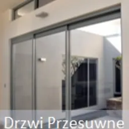 Szklane drzwi przesuwne z aluminiową ramą, prowadzące do wewnętrznego patio z roślinnością, widok z wnętrza budynku.