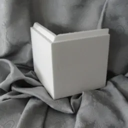 Biały styropianowy element dekoracyjny w kształcie boni na tle drapowanej, wzorzystej, szarej tkaniny.