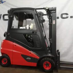 Czerwono-czarny wózek widłowy Linde H16D z kabiną, widok z boku na tle białej ściany.