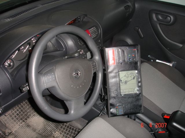 Wnętrze Opla z podłączonym urządzeniem diagnostycznym Launch, widocznym na siedzeniu pasażera, z ekranem prezentującym schemat samochodu.