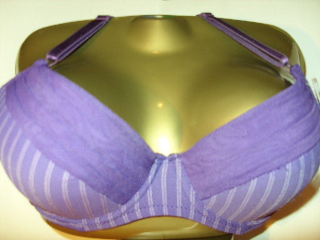 Fioletowy biustonosz w białe paski na złotym manekinie, z fioletowymi ramiączkami i wstawką z siateczki.