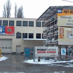 Widok na fasadę składu budowlanego w Bydgoszczy z reklamami materiałów budowlanych, widoczne regały z towarem, palety z cegłami Ytong i baner Porotherm.