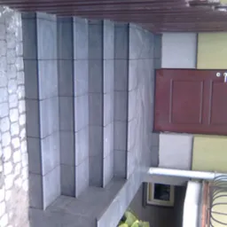 Schody wejściowe wyłożone ciemną, grafitową terakotą, prowadzące do drzwi wejściowych. Widoczne detale wykończenia elewacji.