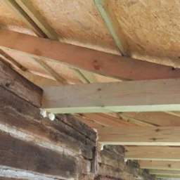 Wnętrze remontowanego drewnianego domu z widocznym ociepleniem pianką i nową konstrukcją dachu z płyt OSB.