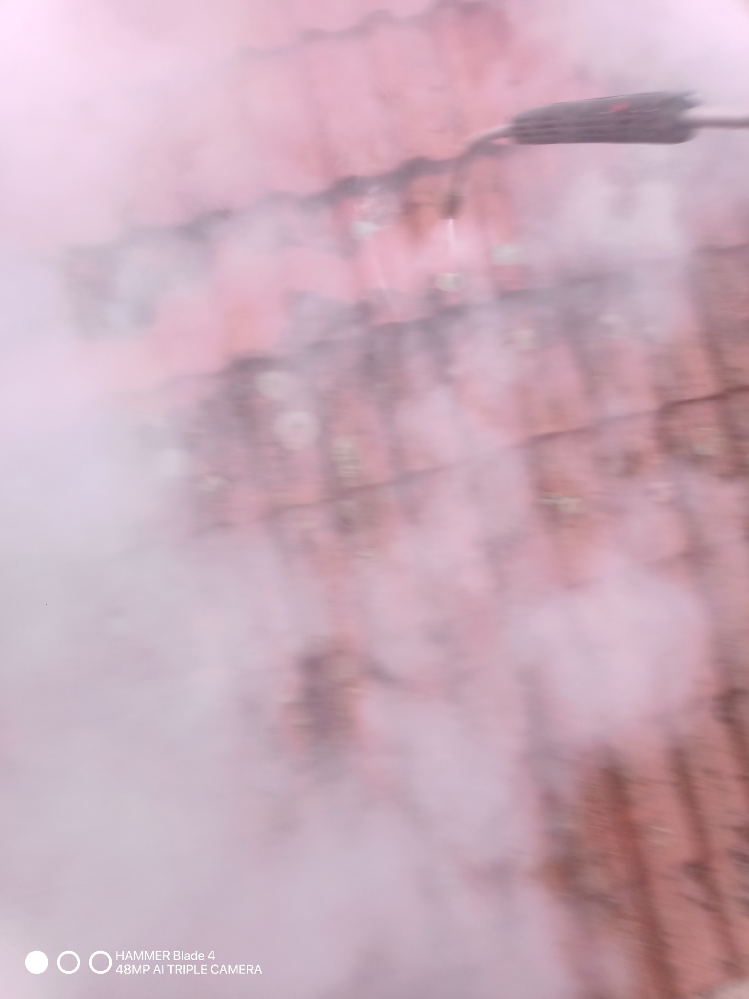 Rozmyte ujęcie dachu pokrytego czerwoną dachówką, spowitego w gęstej, białej mgle, prawdopodobnie podczas czyszczenia lub dezynfekcji. W tle widoczny fragment dyszy rozpylającej. Zdjęcie o niskiej...