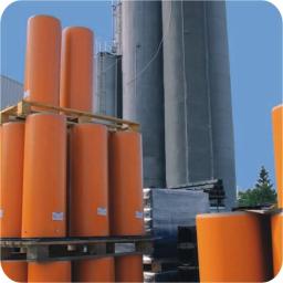 ZHU Jerzy Dejek - Pomarańczowe, cylindryczne zbiorniki na paletach, w tle silosy i błękitne niebo.