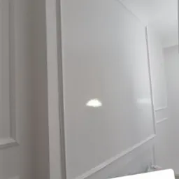 Biała ściana z dekoracyjnymi listwami i sztukaterią, świeżo po malowaniu, z widocznym połyskiem farby.