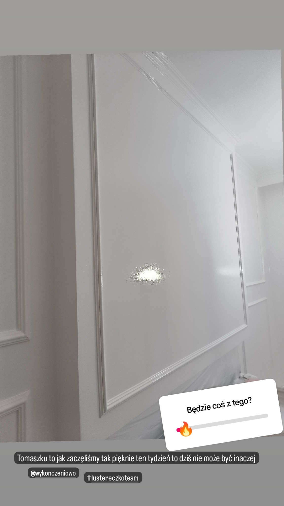 Biała ściana z dekoracyjnymi listwami i sztukaterią, świeżo po malowaniu, z widocznym połyskiem farby.