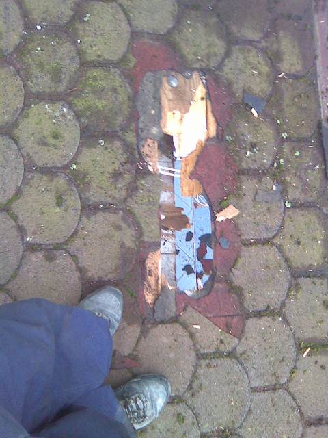 Uszkodzone krycie dachu z widocznymi fragmentami starego poszycia i podkładu, sfotografowane z perspektywy osoby stojącej obok.