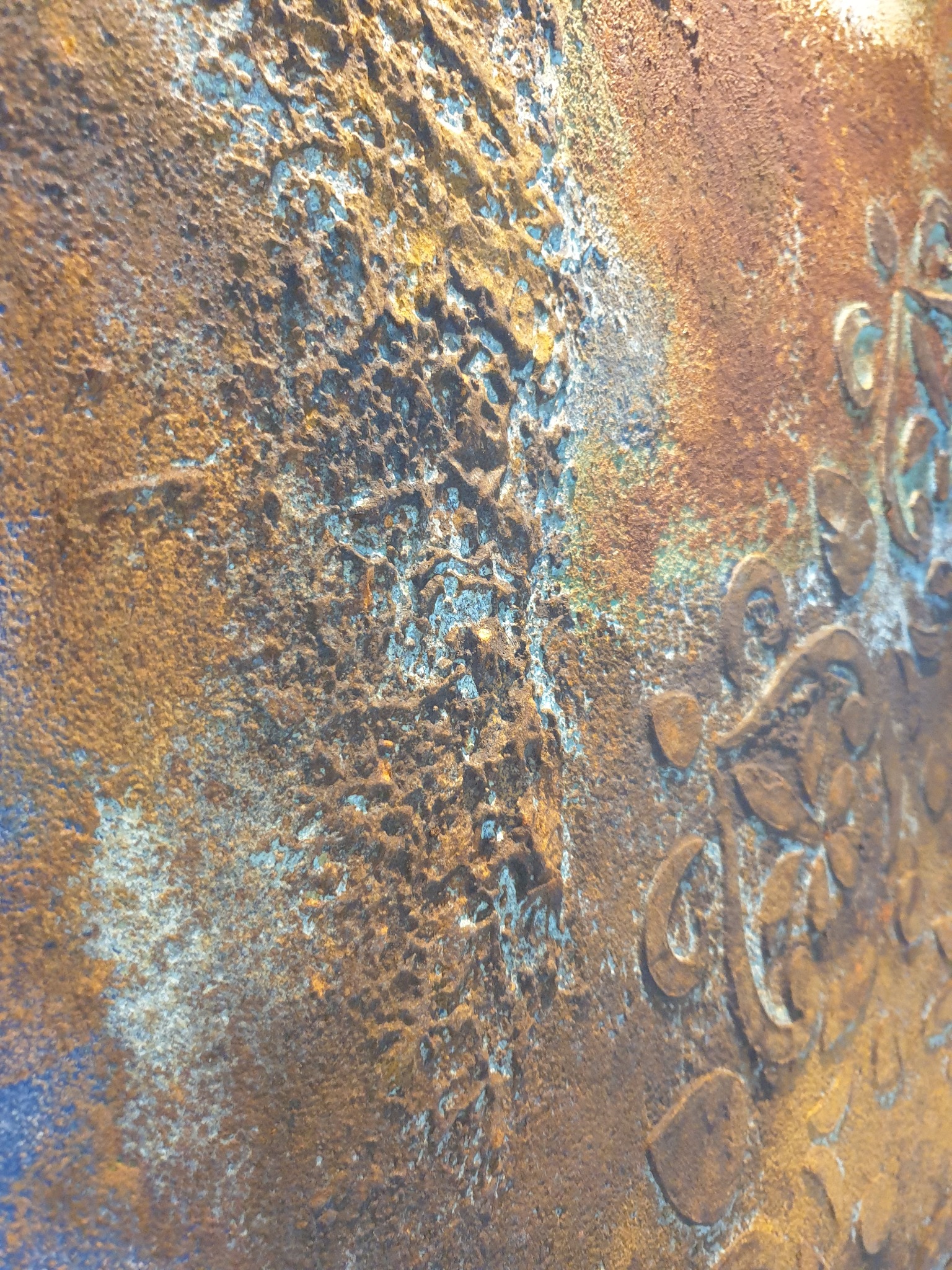 Dekoracyjna, teksturowana ściana w odcieniach brązu i niebieskiego z wytłoczonym wzorem roślinnym. Ujęcie z bliska, ukazujące detale faktury i kolorystyki.