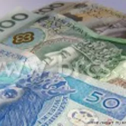 Stos banknotów polskich złotych o nominałach 50 i 100 zł, ułożonych warstwami, lekko rozmyte tło.