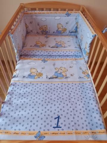 Dwu-elementowa pościel do łóżeczka dziecięcego, z motywem misia w ogrodzie i cyfrą '1' na prześcieradle, w drewnianym łóżeczku.