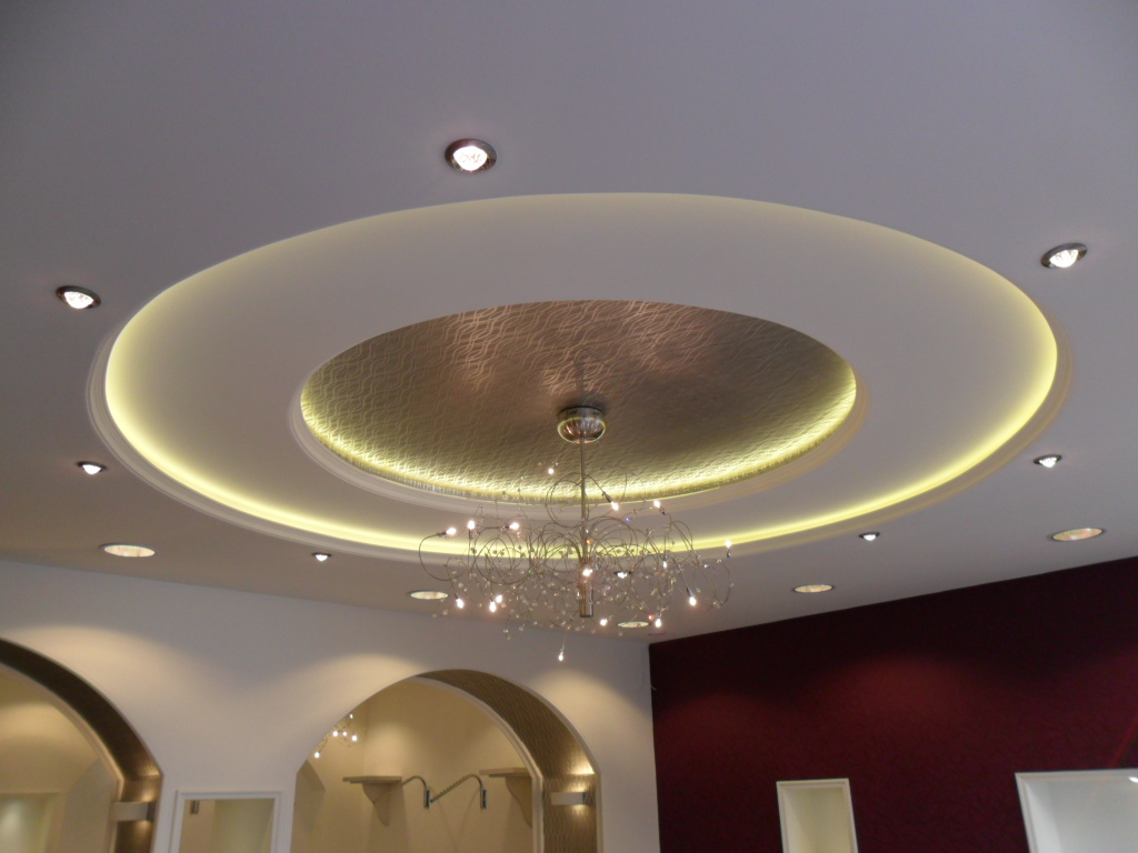 Dekoracyjny sufit podwieszany z oświetleniem LED i wzorzystym centralnym panelem, uzupełniony nowoczesnym żyrandolem.