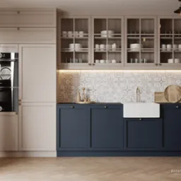 Nowoczesna kuchnia z granatowymi szafkami dolnymi, beżowymi szafkami górnymi z przeszklonymi frontami, białym zlewozmywakiem farmerskim i wzorzystą mozaiką nad blatem, oświetlona wiszącą lampą i...