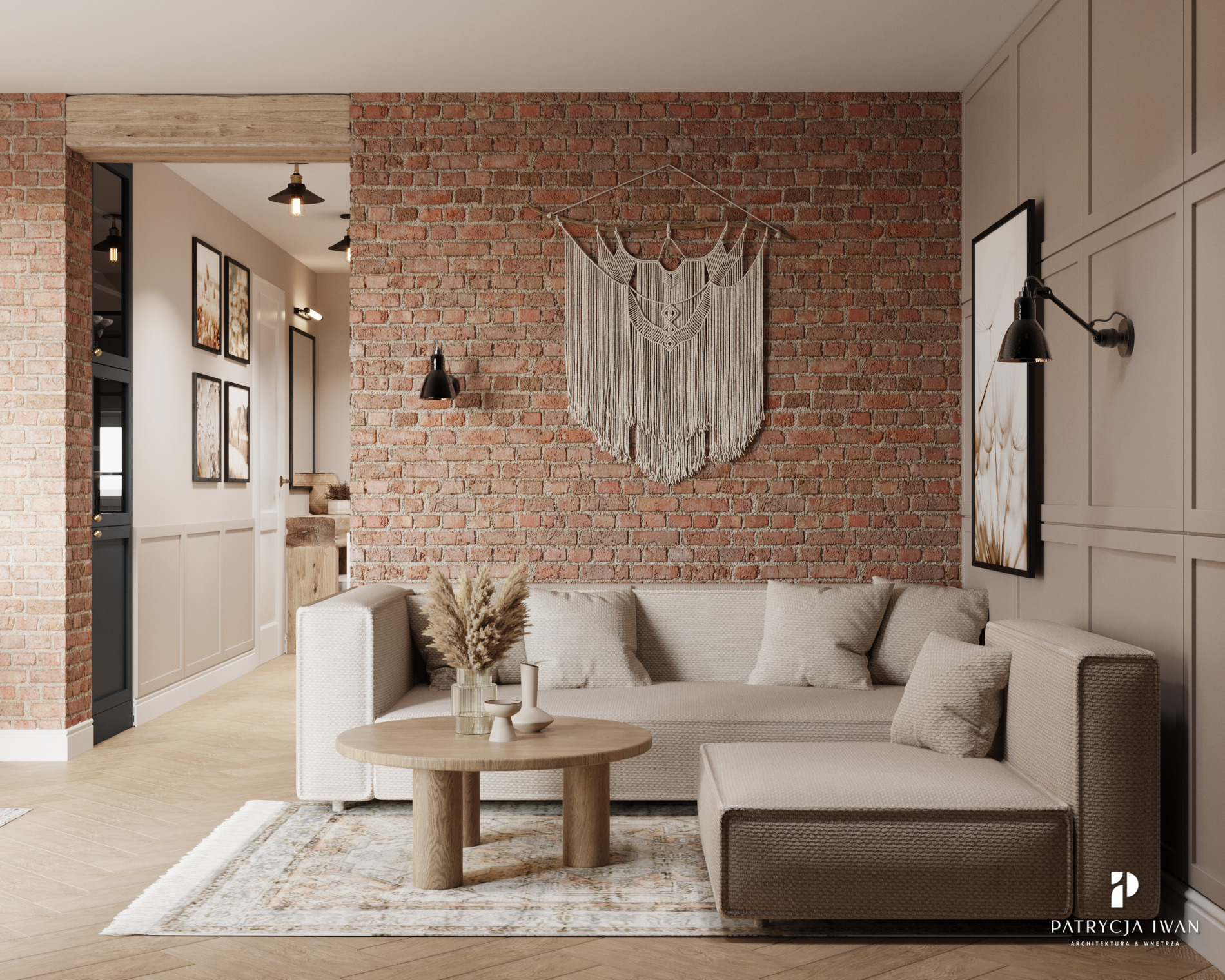 Salon w stylu rustykalnym z ceglaną ścianą, beżową sofą modułową, okrągłym drewnianym stolikiem kawowym i dekoracyjnym makramem na ścianie. Widoczny fragment przedpokoju z galerią obrazów.