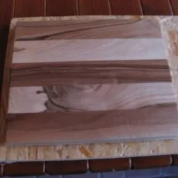 Próbka parkietu z orzecha włoskiego, ułożona na płycie OSB, ukazująca naturalne usłojenie drewna i odcienie brązu.