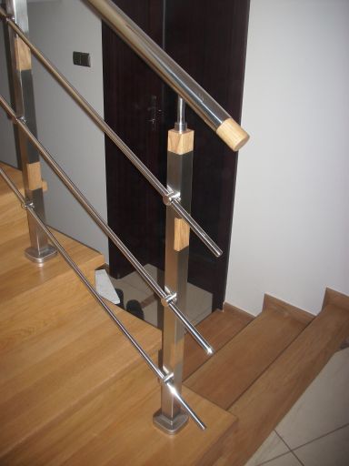 Wnętrze domu z drewnianymi schodami i balustradą ze stali nierdzewnej z drewnianymi elementami mocującymi, widok z góry na stopnie.