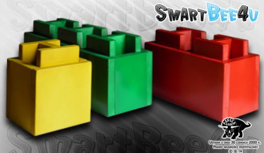 Trzy kolorowe, stylizowane na klocki Lego ławki SmartBee4u: żółta, zielona i czerwona, ustawione na szarym tle z logotypem firmy.