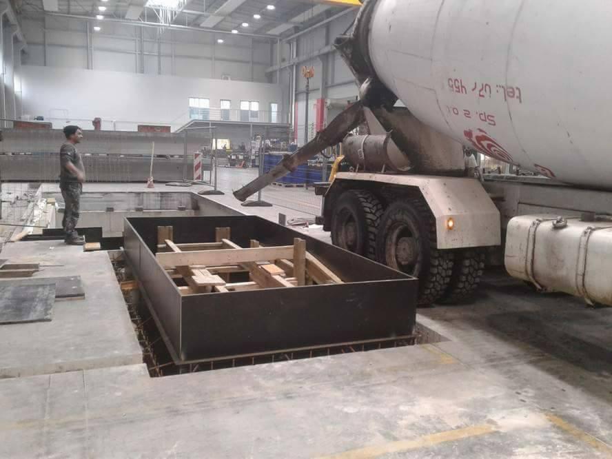 Betoniarka wylewa beton do przygotowanego szalunku na budowie w Popielowie, widoczny pracownik w oddali.