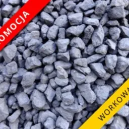 Góra antracytowego, drobnego węgla kamiennego z naklejkami promocyjnymi w kolorze czerwonym i żółtym, informującymi o promocji i workowaniu.