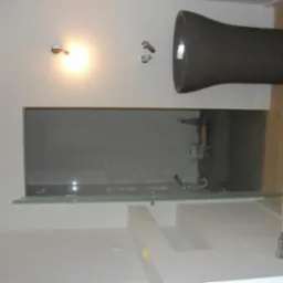 Nowoczesna łazienka z designerską umywalką w kształcie kielicha, kabiną prysznicową ze szklaną ścianą i minimalistyczną armaturą. Jasne drewno na podłodze.