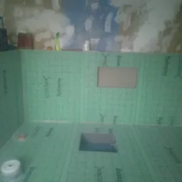 Przygotowanie do hydroizolacji brodzika: ściany i podłoga wyłożone zieloną matą hydroizolacyjną Codex Hydrostop, widoczne otwory na odpływ i element ścienny, surowe ściany w tle.