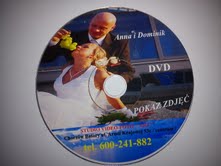 Płyta DVD z nadrukowanym zdjęciem pary młodej (Anna i Dominik) podczas wesela, panna młoda z kiścią winogron w ustach, widoczny napis 'POKAZ ZDJĘĆ' oraz dane kontaktowe studia video-foto.
