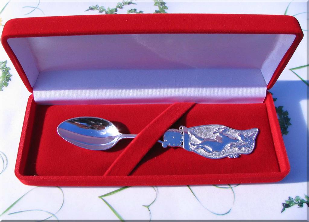 Srebrna łyżeczka z grawerem smoczka i renifera w czerwonym welurowym pudełku prezentowym, idealna na chrzest lub roczek.