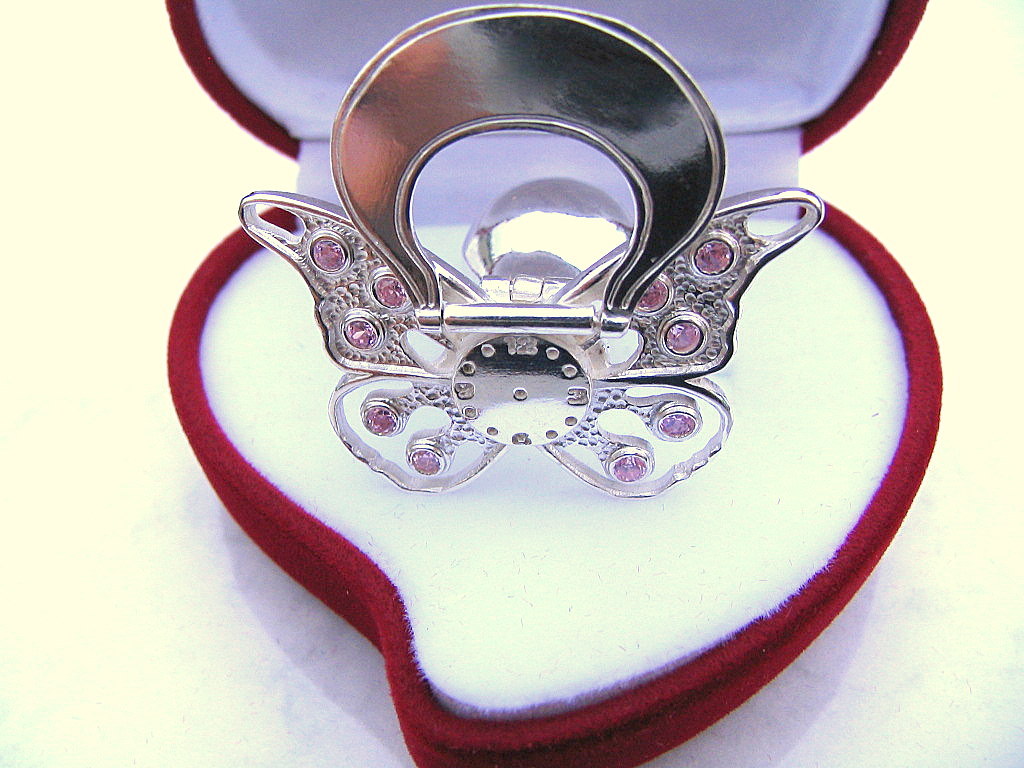 Srebrny smoczek-grzechotka z różowymi kamieniami w czerwonym pudełku w kształcie serca.
