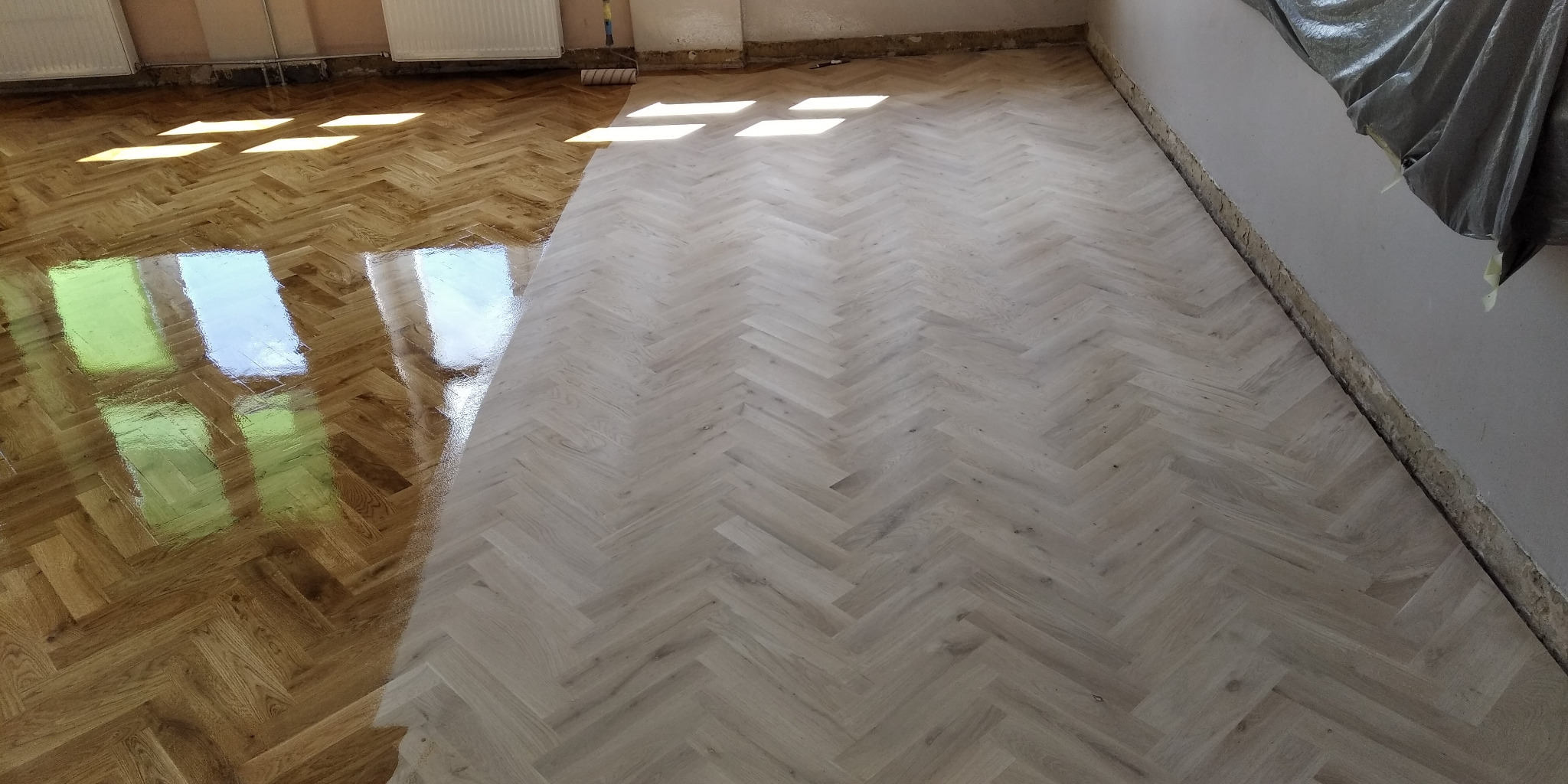 Częściowo odnowiona podłoga parkietowa w jodełkę, z widoczną różnicą w kolorze i połysku między odnowioną a nieodnowioną częścią.