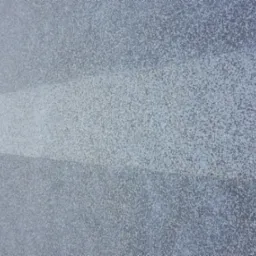 Szara elewacja z widocznymi poziomymi pasami, prawdopodobnie świeżo pomalowana, z delikatną strukturą ziarnistą.