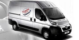 Srebrny furgon marki Peugeot Boxer z logo 'Trans Serwis' na boku, zaparkowany na jasnym tle.