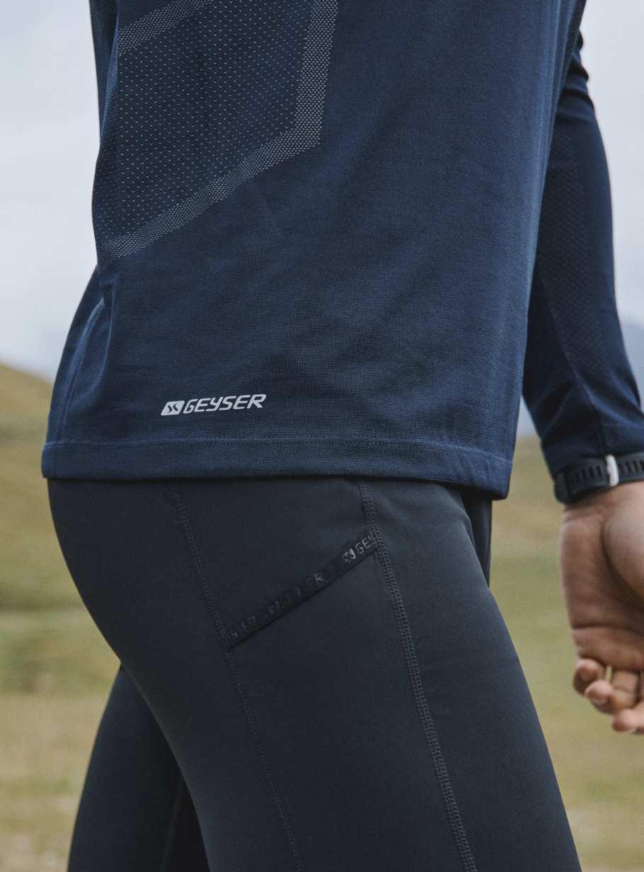 Granatowa koszulka termoaktywna z długim rękawem i legginsy sportowe z logo Geyser, widok z boku na tle łąki.