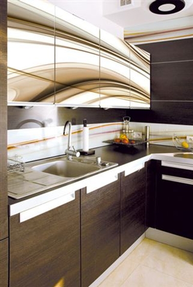 Nowoczesna kuchnia z ciemnobrązowymi szafkami z białymi uchwytami, metalowym zlewozmywakiem i baterią, oraz górnymi szafkami z abstrakcyjnym wzorem w odcieniach beżu i brązu.