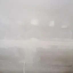 Widok sufitu po szpachlowaniu, z widocznymi śladami po łatach i wystającym przewodem elektrycznym, przygotowany do dalszych prac wykończeniowych.