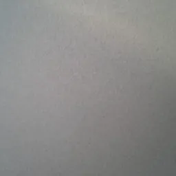 Szary, jednolity tynk na ścianie, widoczna faktura, oświetlenie z góry. Delikatne cieniowanie. Minimalistyczny detal wykończenia wnętrza.