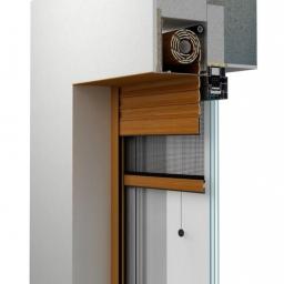 Daniel Jasic - Przekrój okna z roletą zewnętrzną w kolorze drewna, widoczne detale konstrukcyjne i mechanizm zwijania, na tle białej ściany i surowego betonu.