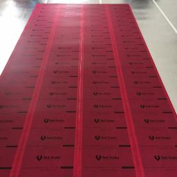 AZ TERMO-EFEKT Termowizja,folia grzewcza na podczerwień - Rozłożone, czerwone maty grzewcze marki Red Snake na błyszczącej, szarej powierzchni podłogi, przygotowane do instalacji.