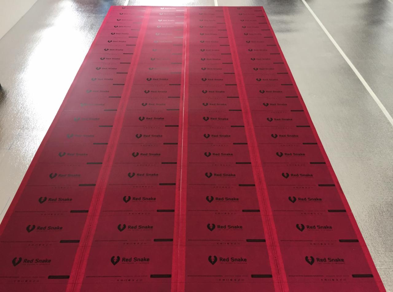 Rozłożone, czerwone maty grzewcze marki Red Snake na błyszczącej, szarej powierzchni podłogi, przygotowane do instalacji.