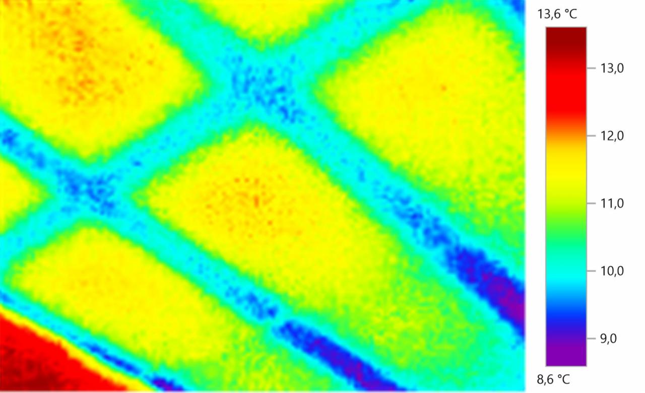 Termowizja fragmentu ściany z widocznymi mostkami termicznymi w postaci chłodniejszych, niebieskich linii na tle cieplejszych, żółtych obszarów, z legendą temperatur po prawej stronie.