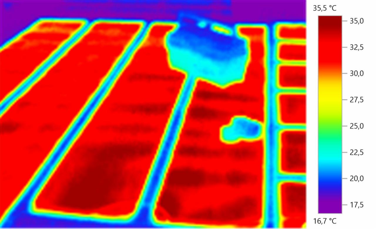 Termowizyjne zdjęcie podłogowego ogrzewania, ukazujące rozkład temperatur na powierzchni paneli, z widoczną skrzynką rozdzielczą i legendą temperatury w stopniach Celsjusza po prawej stronie.