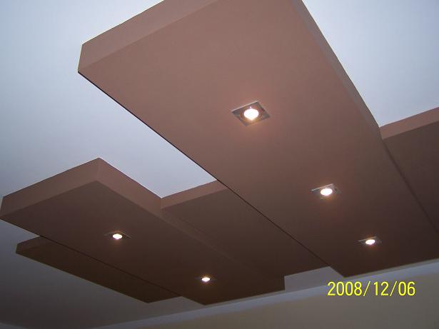 Kaskadowy sufit podwieszany z płyt kartonowo-gipsowych w odcieniach brązu, oświetlony punktowymi lampami halogenowymi, widok z dołu.