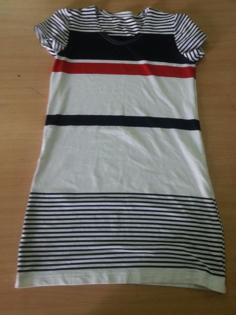 Letnia sukienka w paski, biało-granatowo-czerwona, leżąca na drewnianym stole.